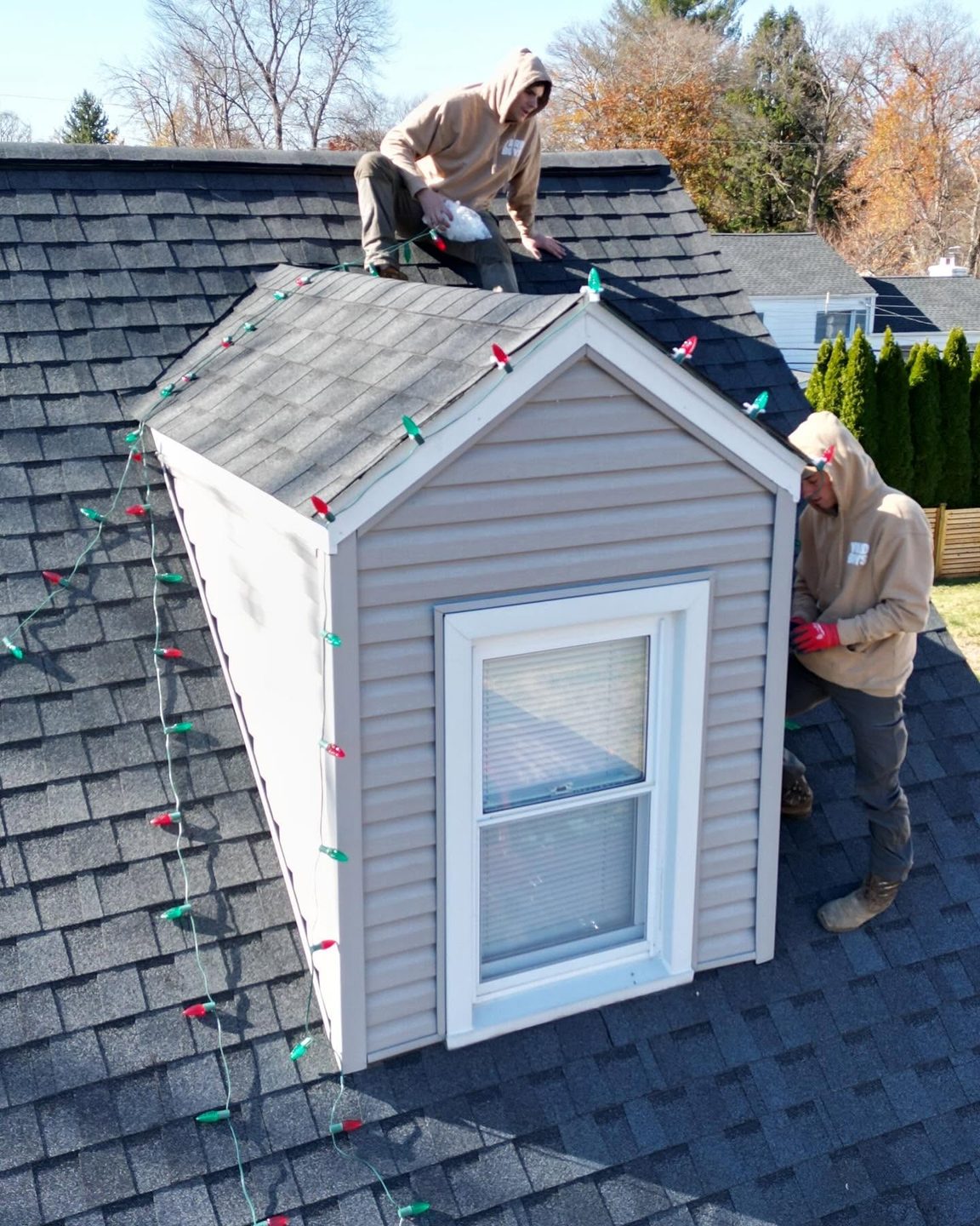 Yard Boys crew clipping red and green C9 lights onto a dormer