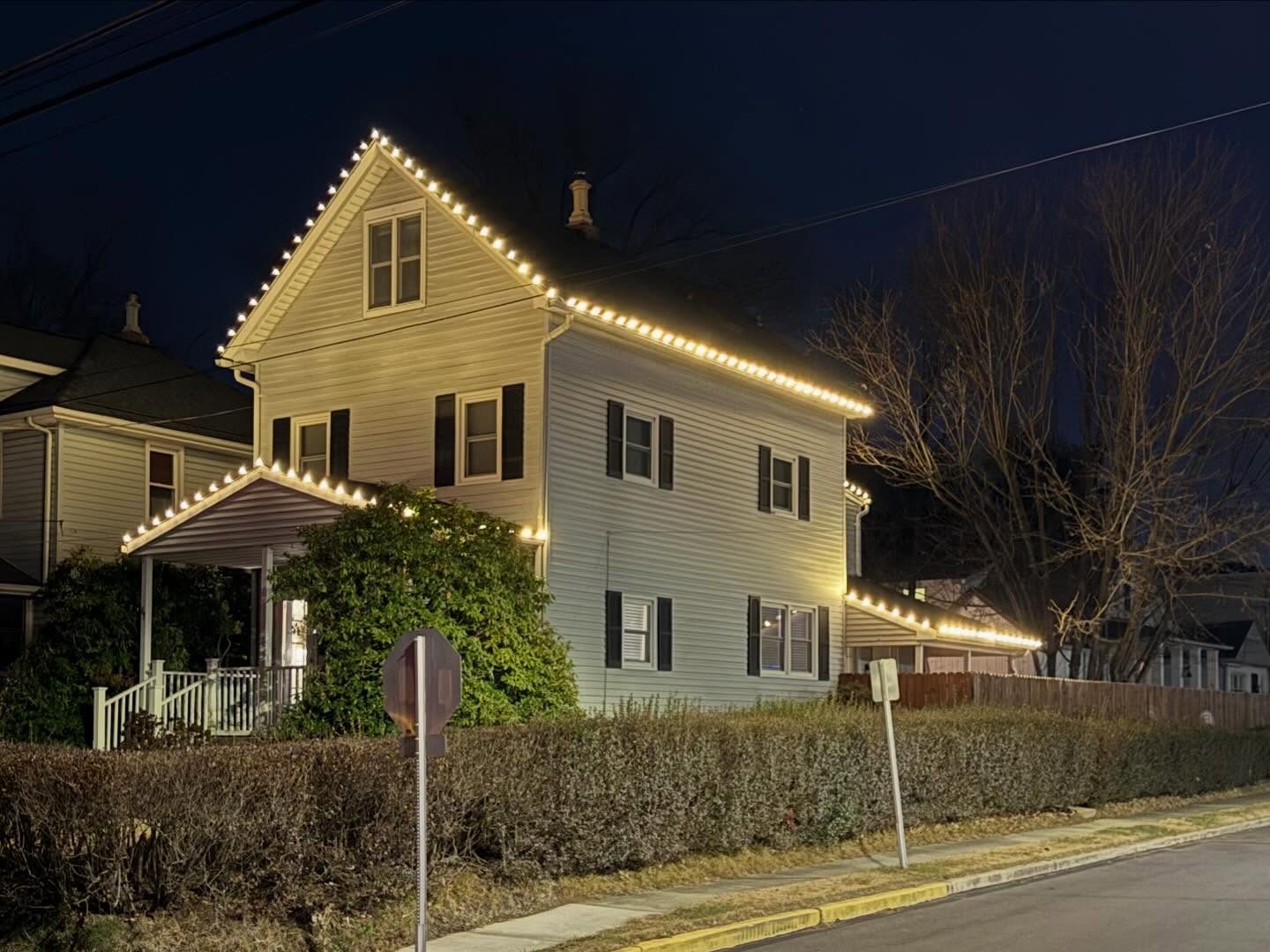 Warm white lights on the gables and porch of a two story home