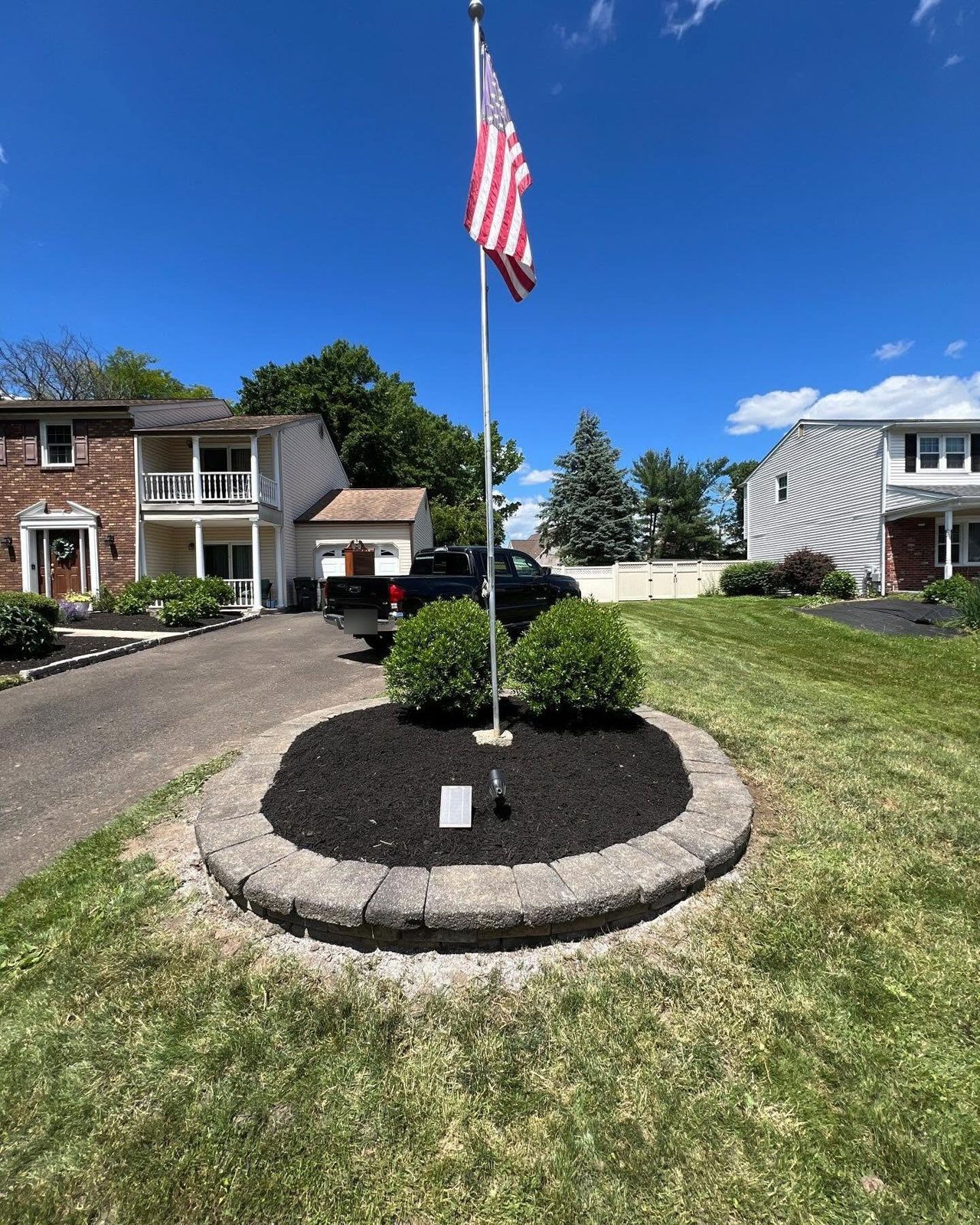 Boxwoods trimmed into clean rounds in a flagpole bed