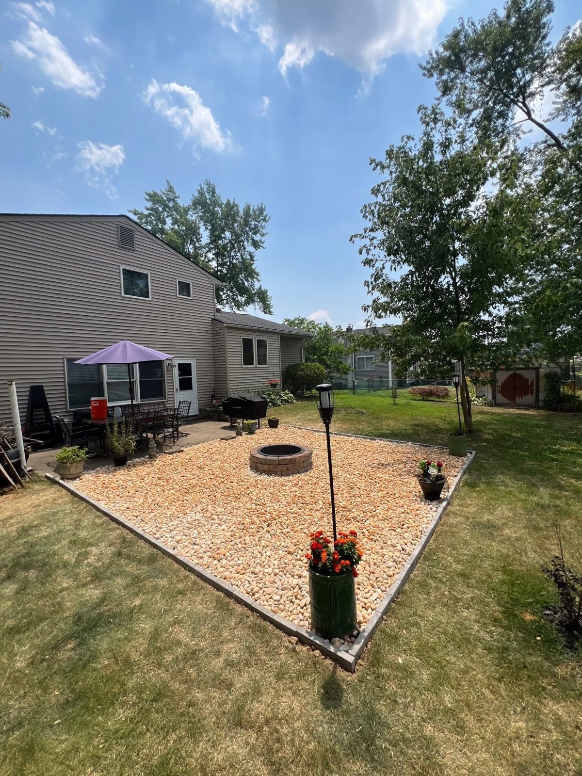 Backyard fire pit area with river rock and a paver border next to the patio