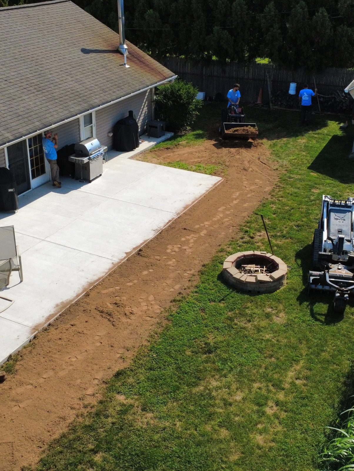 Ground graded and prepped along a concrete patio, seen from above