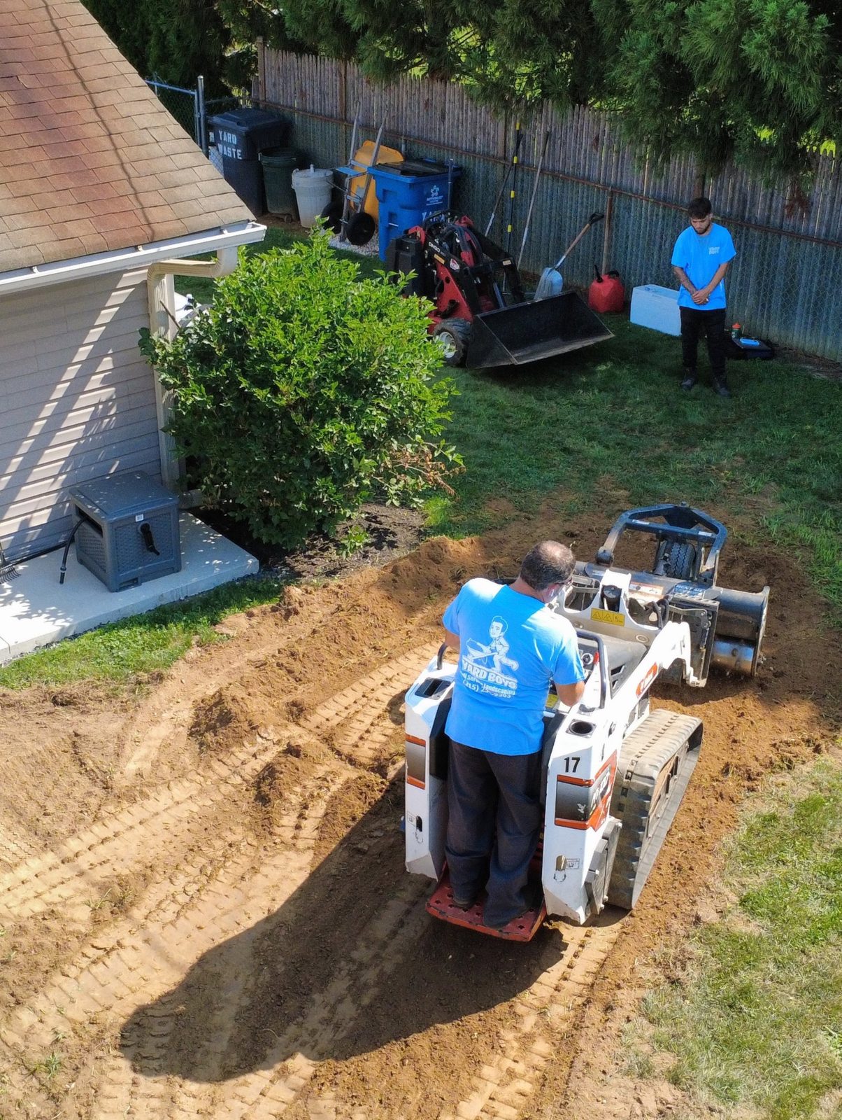 Yard Boys crew grading a backyard with a compact track loader